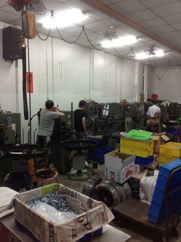 弘志彈簧工廠多位人員於成排機台旁作業，前方可見線材與零件周轉容器